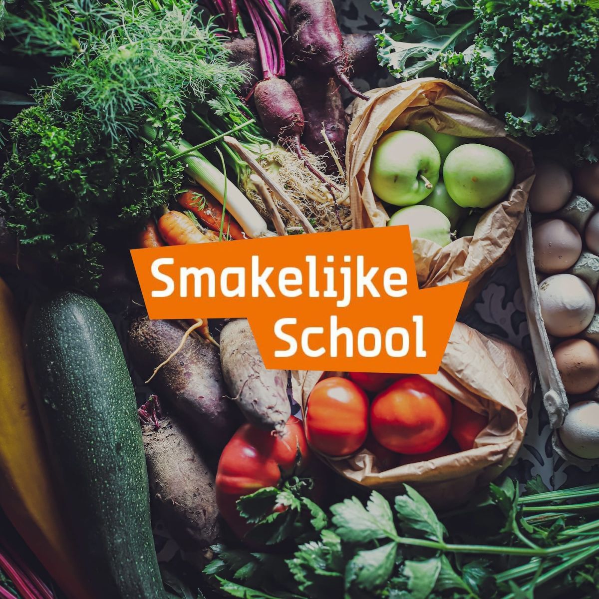 Het logo van Smakelijke school met als achtergrond een heleboel verse groenten