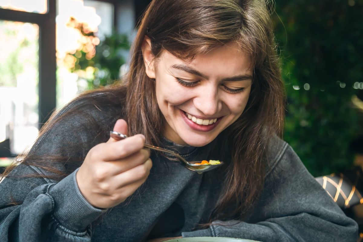 Een vrouw die al lachend verse soep van Soepréme eet